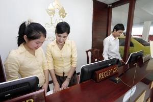 two women are looking at a register in a store at Lao Golden Hotel in Ban That-Louang