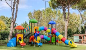 une aire de jeux avec un toboggan coloré dans un parc dans l'établissement Camping Village Costa Est, à Riotorto