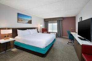 Hilton Garden Inn Chesapeake Greenbrier في تشيسابيك: غرفة فندقية مع سرير وتلفزيون بشاشة مسطحة