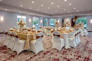 Hilton Garden Inn Chesapeake Greenbrier في تشيسابيك: قاعة احتفالات مع طاولات وكراسي بيضاء