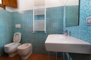 W wyłożonej niebieskimi kafelkami łazience znajduje się umywalka i toaleta. w obiekcie Il Casale Del Giglio w mieście Santo Stefano di Magra