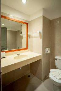 a bathroom with a sink and a toilet and a mirror at Jansom Beach Resort in Ranong