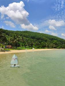 a small sail boat in the water on a beach at Jansom Beach Resort in Ranong