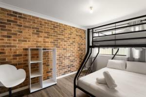 een slaapkamer met een hoogslaper en een bakstenen muur bij Aqua on Achilles in Nelson Bay