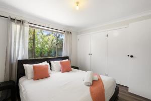 een slaapkamer met een bed met oranje en witte kussens bij Aqua on Achilles in Nelson Bay