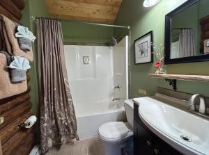 a bathroom with a tub and a toilet and a sink at Cozy Log Cabin In Pristine Nature in Nelson +33 photos