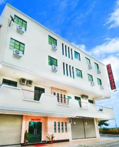 a large white building with windows on a street at Bay Hotel in Lahad Datu +28 photos