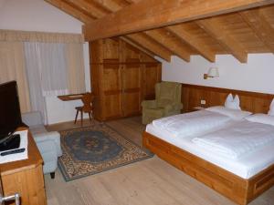 een slaapkamer met een bed, een bureau en een televisie bij Chalet Ciasa Alexander in San Cassiano