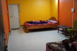Cholo Ghure Ashi-Sillery Gaon Homestay في Pedong: غرفة نوم بسرير وجدار اصفر
