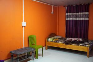 Cholo Ghure Ashi-Sillery Gaon Homestay في Pedong: غرفة نوم بجدران برتقالية وسرير وكرسي