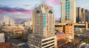 a tall building in a city with tall buildings at City Comfort Inn Wuhan Jianghan Road Jiali Square in Wuhan