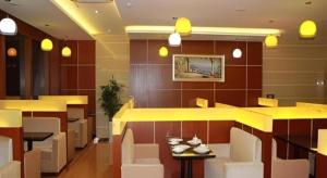 a restaurant with a yellow counter and white chairs at GreenTree Inn Jiaxing Zhongan Business Hotel in Jiaxing