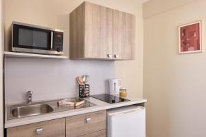 eine Küche mit Spüle und Mikrowelle in der Unterkunft Zenitude Quality Aparthotel Le Havre les docks in Le Havre