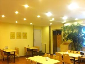 7 Days Inn Qingdao Haier Zone Ditie Tower Jiushui West Road في Laoshan: مطعم ذو جدران وطاولات وكراسي صفراء