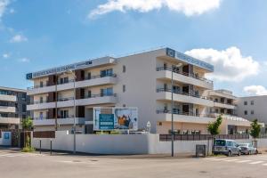 Quality Suites Perpignan Prestige في بيربينيا: مبنى سكني فيه سيارات تقف امامه