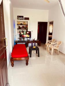Kannada Maathe Home Stay- Golden Temple-Tibet camp 2 km far في كوشالناغار: غرفة معيشة مع كرسي احمر وطاولة