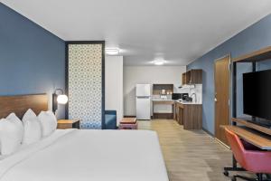 Everhome Suites Bowling Green في بولينغ غرين: غرفة فندقية بسرير كبير ومطبخ