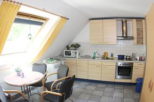 eine Küche mit einem Tisch und Stühlen sowie einem Tisch und einem Fenster in der Unterkunft Pension Büürma in Papenburg