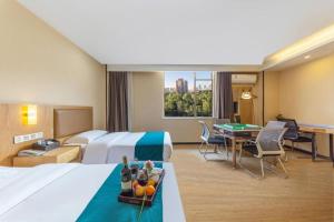 a hotel room with a bed and a desk with a table at GreenTree Inn Huangshi Huahu Development Zone Daquan Road in Huangshigang +250 photos