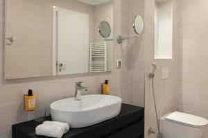 a bathroom with a sink and a toilet and mirrors at Apeiro City Avant-garde Hotel in Sarajevo