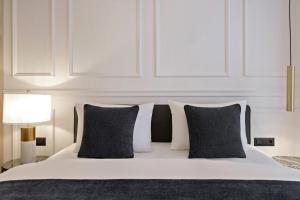 a bedroom with a white bed with black pillows at Apeiro City Avant-garde Hotel in Sarajevo