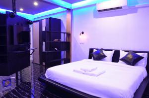 sypialnia z dużym białym łóżkiem z niebieskimi lampkami w obiekcie Maderla w mieście Bangkok