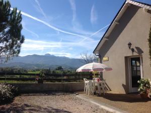 una casa con mesa, sillas y sombrilla en Le Gîte du Poiré, en Molère