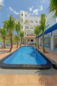 a large swimming pool with palm trees in front of a building at KParis Beach Resort in Bình Sơn