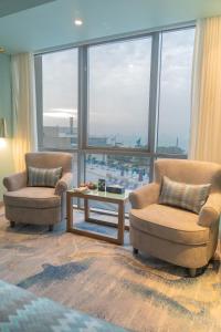 two chairs and a table in a room with a large window at Symphony Style Hotel Kuwait in Kuwait