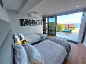 una camera da letto con due letti e una grande finestra di Salt & Soul a Herolds Bay Altre 45 foto