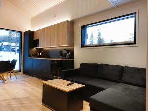 a living room with a black couch and a kitchen at Saarimaja in Syöte
