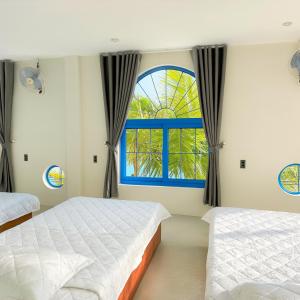 a bedroom with two beds and a window at KParis Beach Resort in Bình Sơn