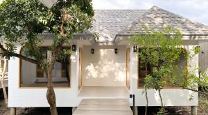 a home with a white front door and trees at rimbaymangrove resort in Ban Khlong Tamru