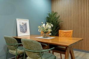 a wooden table with chairs and a vase of flowers on it at Cozy Nest Ladprao - 3BR Townhome 3min walk from MRT in Bangkok