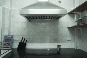 a kitchen with a sink and a hood over a stove at Cozy Nest Ladprao - 3BR Townhome 3min walk from MRT in Bangkok +37 photos