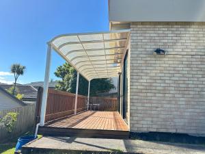 Albany Sunny Deck Retreat في أوكلاند: فناء مع مظلة على جانب المنزل