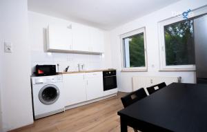 a kitchen with a washing machine and a table with chairs at BEGE APARTMENTS LightHaus in Holzwickede