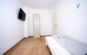 a bedroom with a bed and a flat screen tv at BEGE APARTMENTS LightHaus in Holzwickede