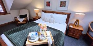 Sandstone Suites - In the heart of Port Fairy في بور فيري: غرفة نوم بسرير وطاولة عليها ورد