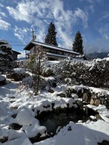 a house in the snow with a pond at 桜Sakura in Omachi