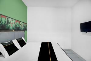 a hotel room with a bed and a tv at Hotel O near Trans Studio Theme Park formerly Sunset Cozy Residence in Mantaak +17 photos