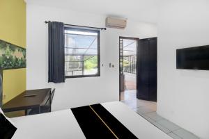 a room with a bed and a desk and a tv at Hotel O near Trans Studio Theme Park formerly Sunset Cozy Residence in Mantaak