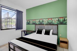 a bedroom with a large bed and a window at Hotel O near Trans Studio Theme Park formerly Sunset Cozy Residence in Mantaak