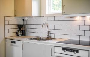 a kitchen with a sink and white tiled walls at Lovely Home In Myggenäs With Sauna in Höviksnäs