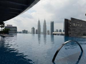 a infinity pool on the roof of a building with a city at Eaton Suites KLCC by Perkasa Ikon in Kuala Lumpur