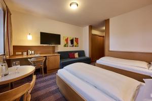 a hotel room with two beds and a desk at Hotel Gasthof Krönele in Lustenau