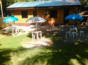 three tables and umbrellas in front of a house at Star Lotus Guesthouse in Sampong