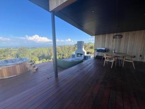 a wooden deck with a hot tub and a table at Golden Ridge Retreat in Otorohanga