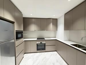a kitchen with gray cabinets and a refrigerator at Eaton Suites KLCC by Perkasa Ikon in Kuala Lumpur