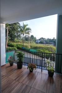 a balcony with potted plants and a view of a park at CaaZa Ventura in Sultan Bathery